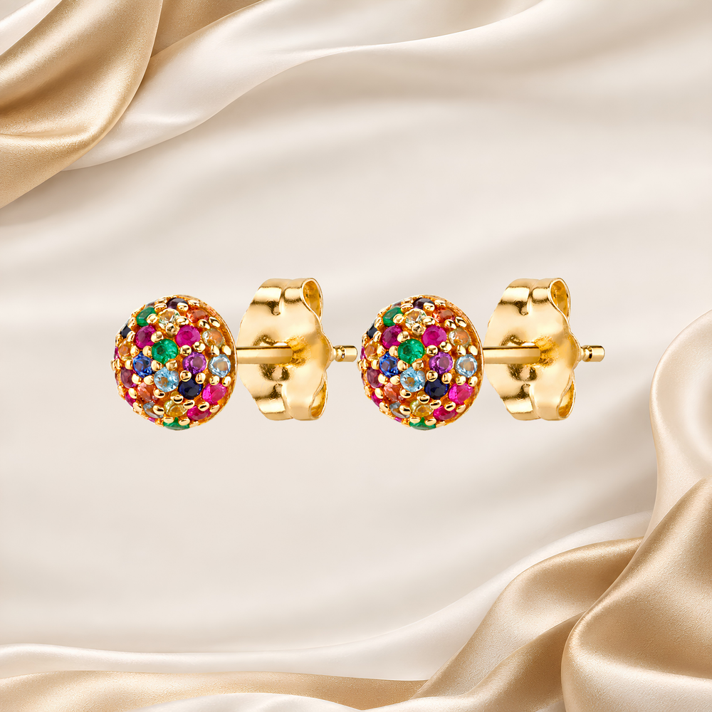 A pair of gold stud earrings with round, multicolored pavé crystal clusters, displayed on a draped cream satin fabric background.