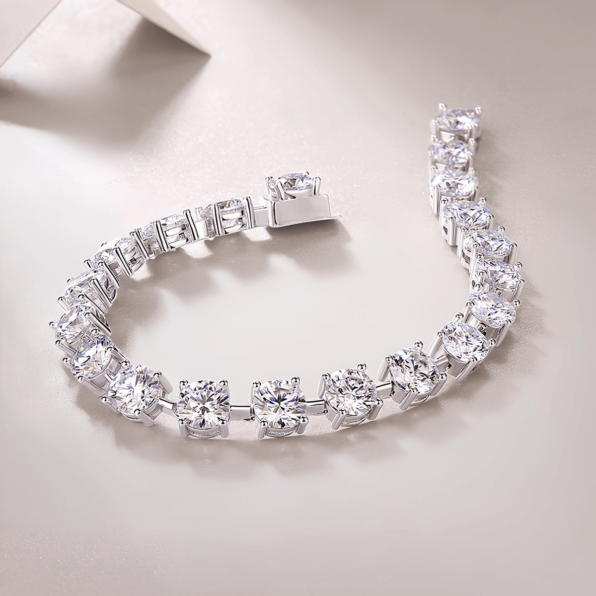 A silver-toned tennis bracelet with clear round-cut gemstones, displayed on a light beige surface.