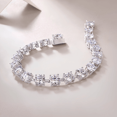 A silver-toned tennis bracelet with clear round-cut gemstones, displayed on a light beige surface.