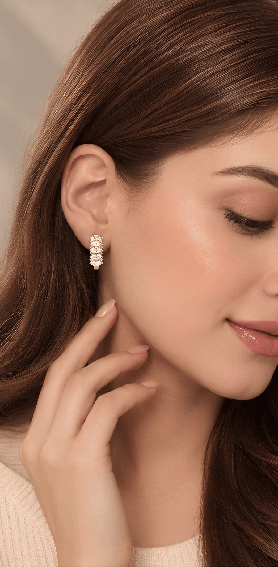 A pair of gold huggie hoop earrings with a vertical stack of oval-cut clear gemstones, shown on a clean white background with one earring facing forward and the other at an angle to show the hinge.