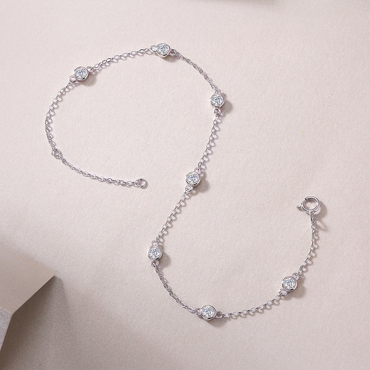 Silver bracelet with diamond-like beads on a light pink background
