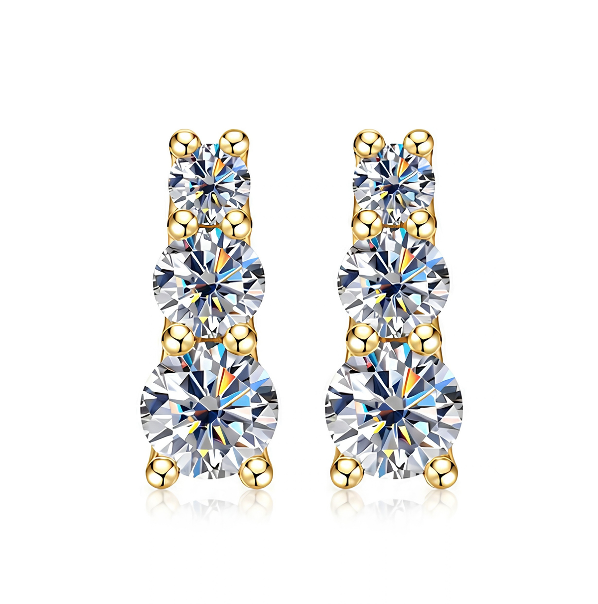 A pair of gold drop earrings with three round-cut clear gemstones in each drop, set in yellow gold prong settings against a white background.