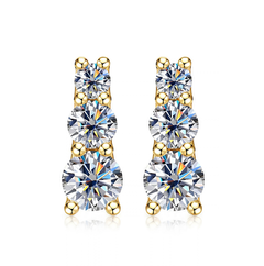 A pair of gold drop earrings with three round-cut clear gemstones in each drop, set in yellow gold prong settings against a white background.