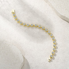 Gold bracelet with clear stones on a light beige background