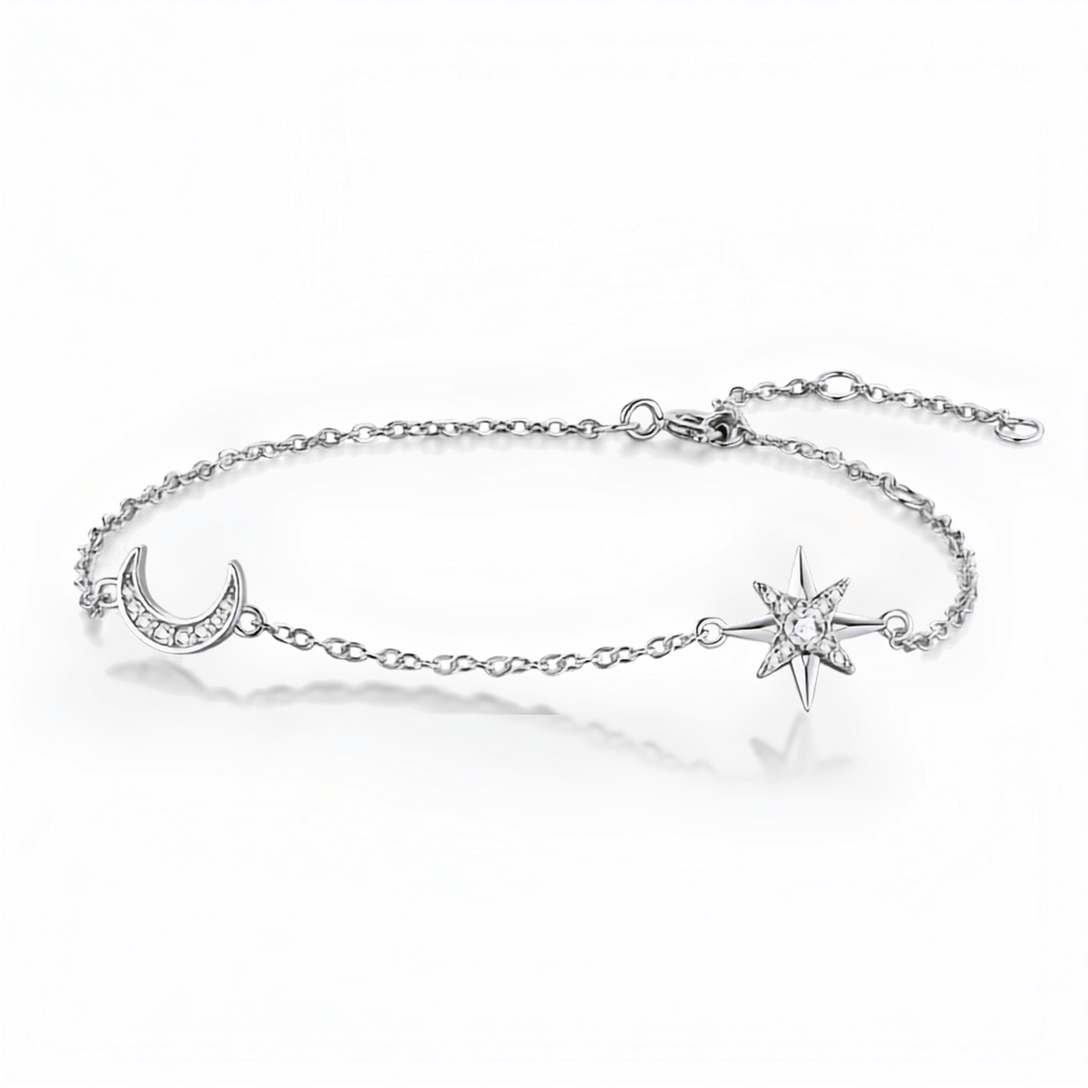A delicate silver chain bracelet featuring a crescent moon charm set with small clear stones and a starburst charm, displayed on a clean white background with a soft reflection.