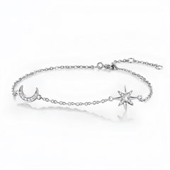 A delicate silver chain bracelet featuring a crescent moon charm set with small clear stones and a starburst charm, displayed on a clean white background with a soft reflection.