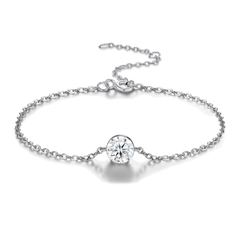 A delicate silver chain bracelet with a single round clear gemstone in a bezel setting, displayed on a clean white background with a soft reflection.