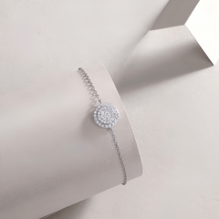 A delicate silver bracelet with a round pavé moissanite bracelet, displayed on a light gray jewelry stand.
