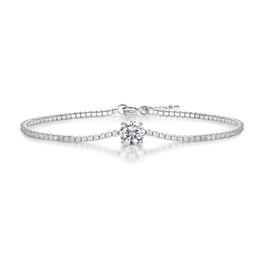 A silver-toned tennis bracelet featuring a central round-cut clear gemstone and a row of small pavé-set stones along the band, shown on a clean white background with a soft reflection.